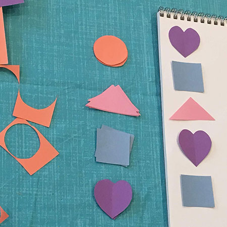 Colorful construction paper cut into hearts, squares, and triangles.